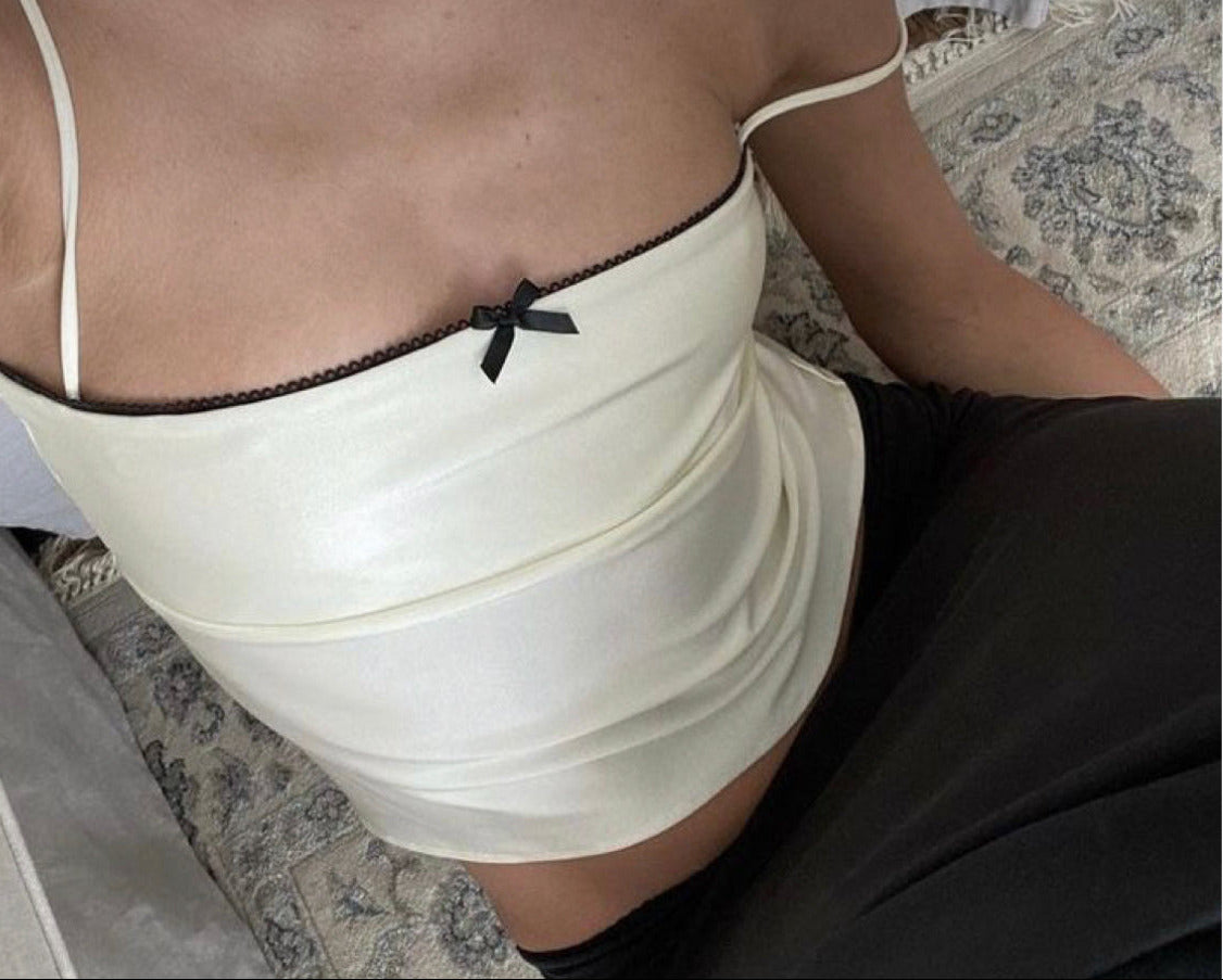 Person wearing a lace trim top with a bow panels on a patterned rug.